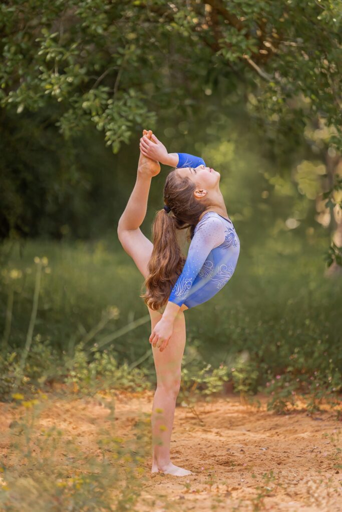 צילומי בת מצווה מתבגרת עם בפארק עם לבוש של אקרובטיקה עושה תרגיל אקרובטי רגל לראש