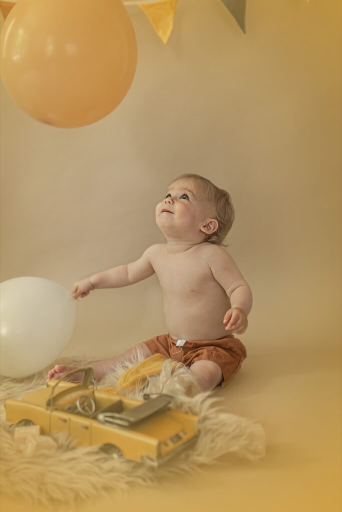 גיל שנה -פעוט מסתכל למעלה לבלון משחק משחקים