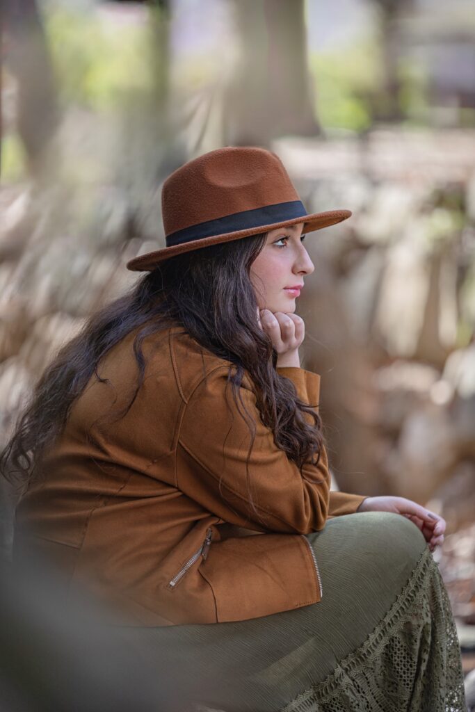 צילומי בת מצווה מתבגרת עם בפארק יושבת עם יד בפנים