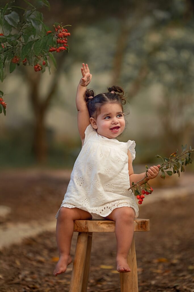 בת שנתיים יושבת על שרפרף ומרימה ידיים