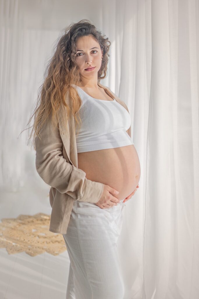צילומי היריון אישה בהריון עומדת ומחבקת את הבטן