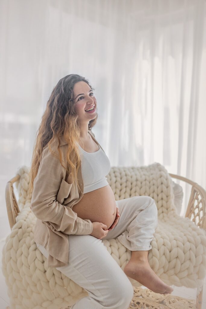 אישה בהריון יושבת עם וילון יפה